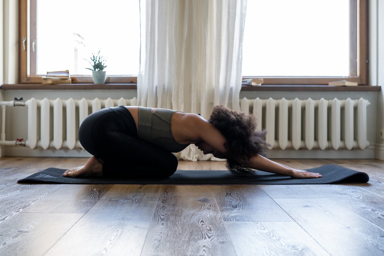 Woman practicing yoga at home on a mat in a cozy room. Embracing fitness and wellness indoors.